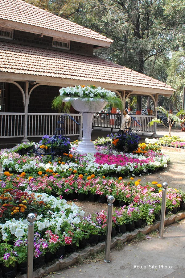 Vibrant flower garden with traditional house at Empress Botanical Garden.​