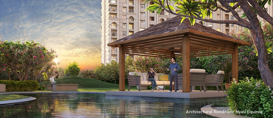 A serene gazebo by a reflective water body surrounded by lush greenery, with a person enjoying a peaceful moment at Nyati Equinox residential complex in Bavdhan